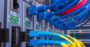 Cables connected to PoE switches stacked together with more in the background.